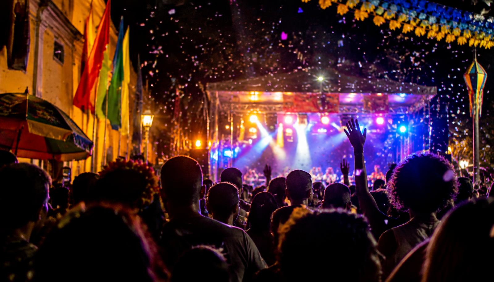 Público em frente a palco iluminado durante festa popular